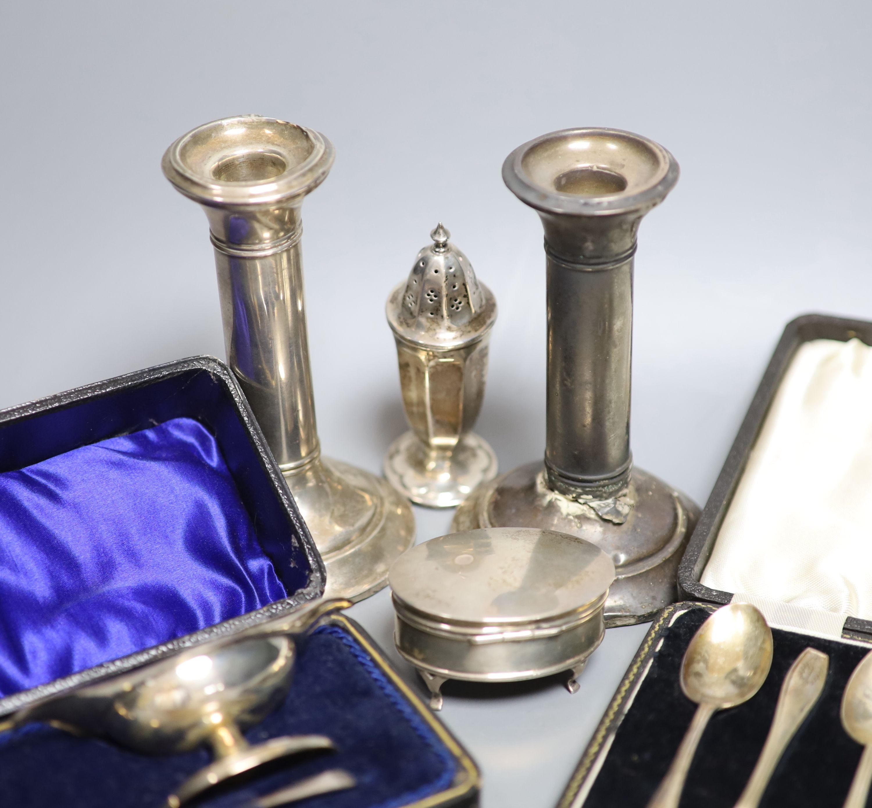 A pair of silver dwarf candlesticks(a,7.f.), 13cm, a small silver trinket box, a silver pepperette and two cased silver sets including a pair of salts and set of six teaspoons.